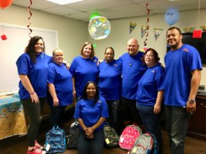 Sapulpa-Tulsa team pose with backpacks filled with school supplies